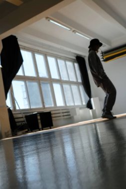 Modern dans hip hop egzersizi. Eski pencereli fotoğraf stüdyosu. Sığ alan derinliğine sahip soyut bulanık arkaplan. Uzayı kopyala Dikey resim.