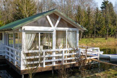 Büyük camlı camlı camlı deniz kenarındaki beyaz kulübe. Teras. Beyaz tekneler. Bahar güneşli sabah.