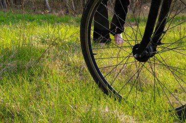 Bisiklet tekerleği ve çıplak ayaklı bir adam sahnesi. Altın saatinde orman çimleri. Yenileyici seyahat konsepti. Boşluğu kopyala.