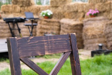 Balyalanmış saman ve müzik aletlerinin bulanık arka planında ahşap sandalye. Rahatlama kavramı.
