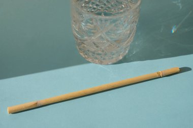 Mavi ferahlatıcı bir yaz arka planında kamışlardan ve kristal bardaklardan yapılmış ekolojik içecek pipetleri. Sert güneş gölgesi. Kendin yap, konsept..