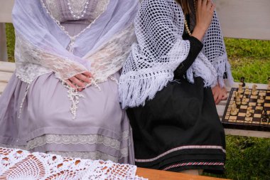 Eski dantel elbiseli kızlar satranç tahtasındaki stilize bir piknikte dinleniyorlar..