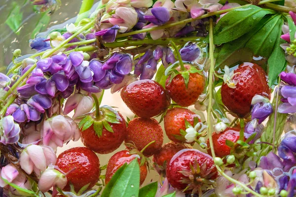 Strawberries and colorful flowers in cool water.