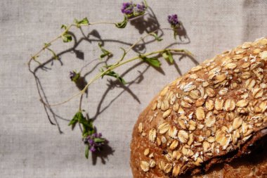 Yulaf ezmeli ekmek ve tuval üzerinde kekik. Doğal güneş ışığı. Sert gölgeler. Üst görünüm.