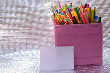 Güneşli bir günde gümüş arka planda bir kutuda okul kırtasiyesi. Beyaz kart modeli. Boşluğu kopyala.