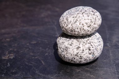 Siyah doğal kayrak üzerinde dekoratif yuvarlak siyah çakıl. Siyah noktadaki beyaz taş. İki taş. Denge. Boşluğu kopyala.