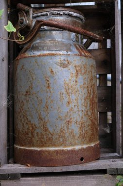 Bahçe süsü olarak tahta bir kutunun içindeki antika süt kutusu. Metal bir plaka üzerinde numara, sahibinin adı ve topluluğun adı var. Dikey resim.