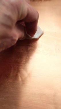 Bakır yüzeyden koli bandı kalıntısı çıkarılıyor. Bakıra odaklan. Sığ alan derinliği.