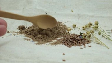 Kaşık içinde keten tohumu unu. Keten bezi üzerinde keten tohumları. Kurutulmuş keten tohumu. Alanın Sığ Derinliği.