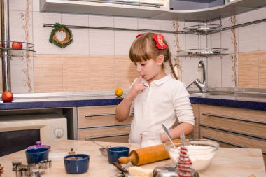 Sevimli mutlu kız Noel kurabiyelerini güzel bir mutfakta pişirmeyi öğreniyor, hamuru yoğuruyor, oklavayla dürtüyor, kurabiyeleri küfle kesiyor, hamuru tadıyor.