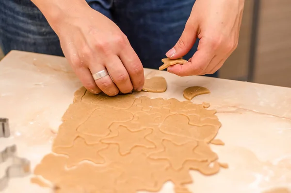 女性の手はクリスマスのためのお祝いのジンジャーブレッドクッキーを準備し 彼女は生地を展開し クッキーカッターでクッキーをカット — ストック写真