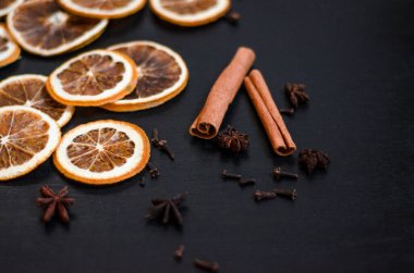 Siyah arka planda sıcak şarap, dağınık kuru portakallar, tarçın, karanfil, yıldız anasonu, kopyalanmış uzay