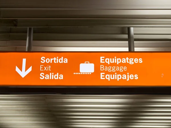 A airport baggage claim sign with suitcase luggage and directional arrow symbols.