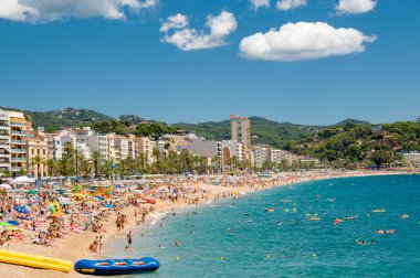LLORET DE MAR, SPAIN -August 09, 2013: A crowd of vacationers enjoy the warm beaches of Costa Brava in Lloret de Mar. clipart