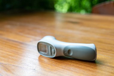 Termometre Tabancası, Dijital Kızılötesi Görüş Ölçüm Aygıtı açık havada ahşap masa üzerinde.