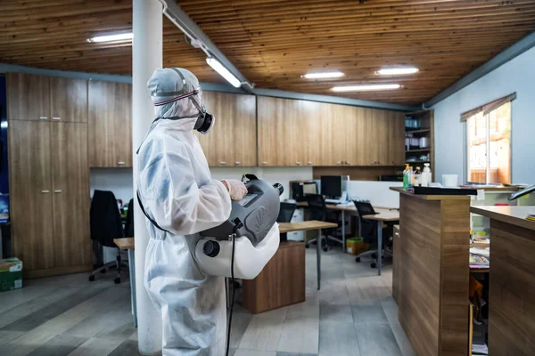 Sterilizasyon makinesi ve su dezenfekte etme ile önleme giysisi içinde profesyonel teknik adam ofis odasındaki tüm alanlara dezenfekte Coronavirus almak için sprey (COVID-19).