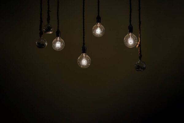 Close up to a group of hanging classic Tungsten Lamp in the dark area with rope.