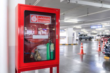 Otopark 'ın köşesindeki itfaiye hortumu kutusu. Kırmızı kutunun ortasındaki Beyaz Tayland Dili harfi, yangın hortumu demek..