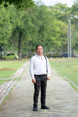 Asyalı, serbest çalışan, uzun saçlı bir adam. Bahçenin bahçesinde yürürken, yanında fotoğraf makinesi vardı..