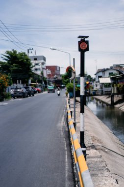 Tayland 'ın doğusundaki Chonburi vilayetinde yol ve kanal arasında sadece kırmızı ışık olan trafik direği..
