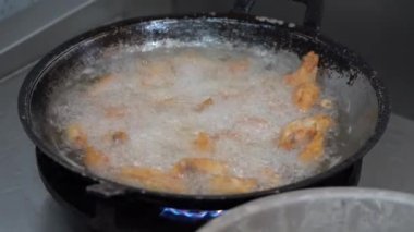 Kızarmış tavuk kanatları tavadaki kızgın yağda kızarıyor..