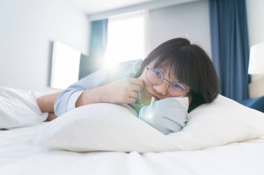 Asyalı genç gözlüklü kadın sabah yatağında yatıyordu..