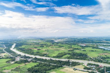 Top view of the Sakae Krang River, Uthai Thani Province where both sides of river are filled with lush green trees. There are community near waterside.