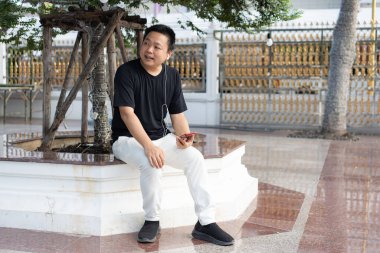 Bir gezgin, yolculuğuna devam etmeden önce tapınak avlusunda dinlenir, müzik dinler ve sakin bir ortamın tadını çıkarır..