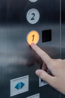 Asansör düğmesine basan bir kızın eli asansörün içindeki düğmeye basan parmağını gösterir..