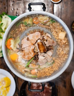 Dilimlenmiş et ve sebzeler et suyu ve buharla dolu metal bir ızgarada pişirilirken merkez de eti kızartır..