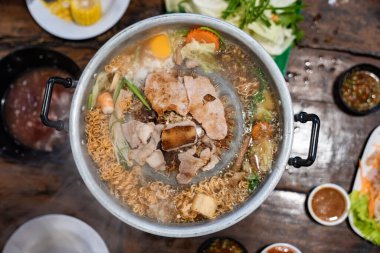 Dilimlenmiş et ve sebzeler et suyu ve buharla dolu metal bir ızgarada pişirilirken merkez de eti kızartır..