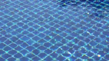 Mavi havuz kiremitleri dalgalı suyun altında ışık yansımalarıyla belirir, çerçeveyi tekrarlayan şebeke kalıpları ve temiz geometrik yüzey ile doldurur..