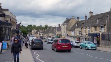 Burford, Oxfordshire, Birleşik Krallık, 12 Temmuz 2023, ana cadde boyunca Stone mimarisi yükselir. Araçlar tarihi şehir ortamında seyahat ederler..