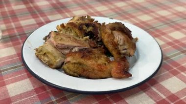 Izgara tavuk parçaları çıtır çıtır derili beyaz bir tabakta dinleniyor. Yemek geleneksel Tayland usulü servis edilir..