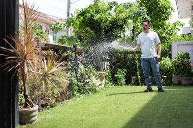 Sakin bir adam bahçesine odaklanarak ve özenle bitkileri sular. An, farkındalığı, sabrı ve doğayla bağlantıyı ifade eder..