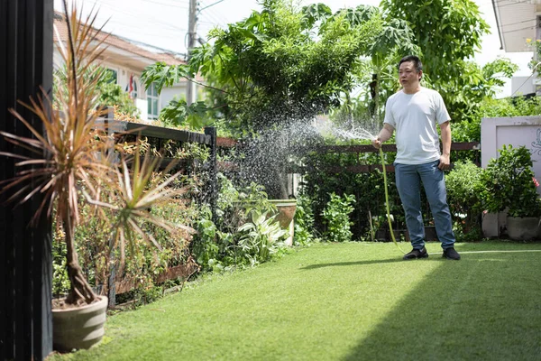 Sakin bir adam bahçesine odaklanarak ve özenle bitkileri sular. An, farkındalığı, sabrı ve doğayla bağlantıyı ifade eder..