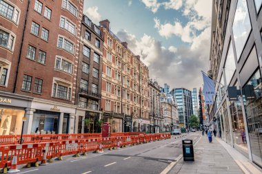 Londra, Birleşik Krallık, 12 Temmuz 2023, Residential caddesi Londra 'nın merkezindeki tuğladan apartmanlarla dolu. Park halindeki arabalar ve yayalar dar bir şehir yolunda ortaya çıkıyor.