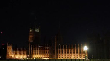 Londra, Birleşik Krallık, 12 Temmuz 2023, Westminster saat kulesi gece aydınlandı. Yayalar köprü boyunca sokak lambaları ve trafik ışıkları altında yürür.