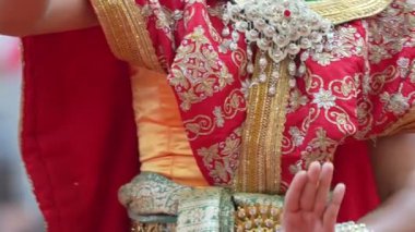 Geleneksel Tayland dansına yakın perspektif ile anlamlı el ve ayak hareketleri üzerine odaklanarak karmaşık kostüm ayrıntıları ve kültürel performans tarzı.