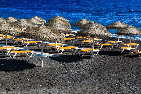 Kamari beach Santorini bedekt met zwarte keien, Griekenland eiland — Stockfoto