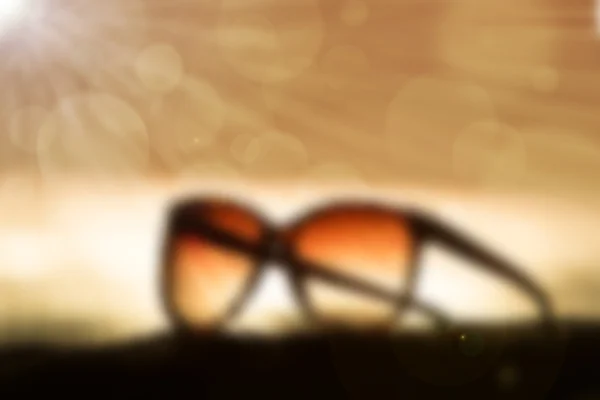 Unscharfe Sonnenbrille bei Sonnenuntergang und Sonnenstrahlen — Stockfoto