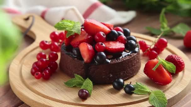 Chocolade taart is versierd met zwarte en rode bessen, aardbeien en munt. — Stockvideo