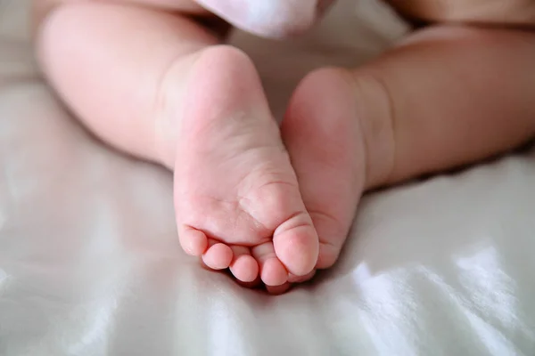 Babys legs on a white bed — Stock Photo, Image