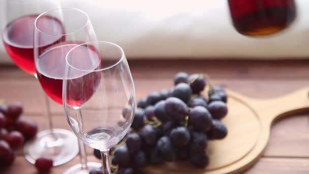 Rotwein wird aus einer Flasche auf hölzernem Hintergrund in ein Glas gegossen — Stockvideo