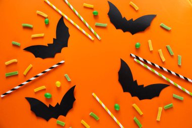 Cadılar Bayramı şekeri ve yarasaları. Turuncu arka plan. Metin için yer