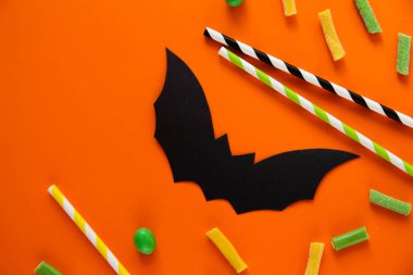 Cadılar Bayramı şekeri ve yarasaları. Turuncu arka plan. Metin için yer