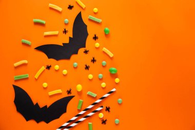 Cadılar Bayramı şekeri ve yarasaları. Turuncu arka plan. Metin için yer