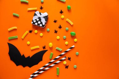 Cadılar Bayramı şekeri ve yarasaları. Turuncu arka plan. Metin için yer