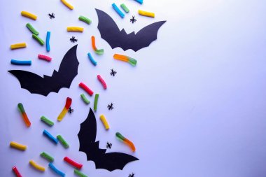 Kağıt Cadılar Bayramı süslemeleri ve beyaz arka planda şekerler. Cadılar Bayramı konsepti. Düz yatış, üst görünüm