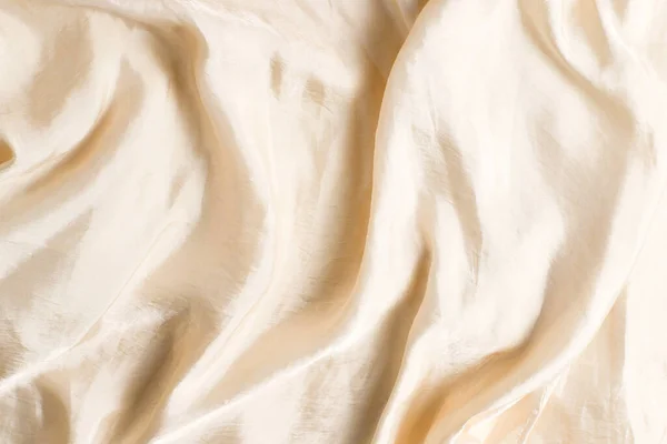 Soft smooth beige silk fabric background. Fabric texture.